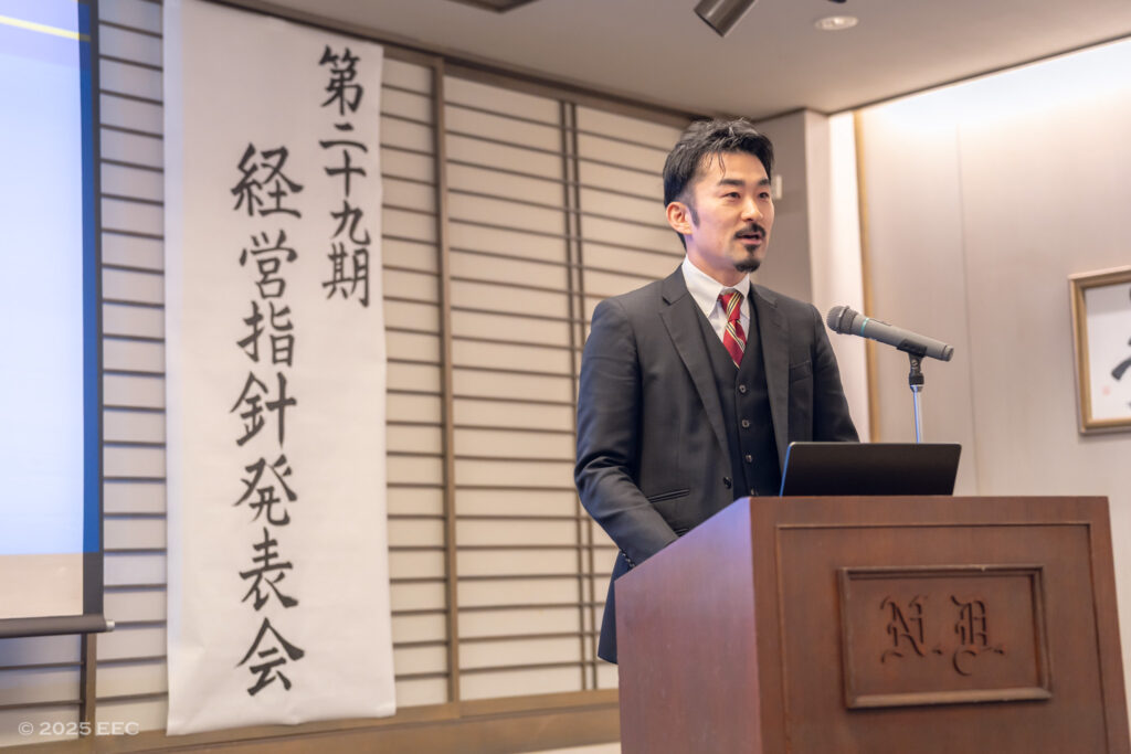 alt="EEC29期の全社方針を発表する代表の田中翔紘"